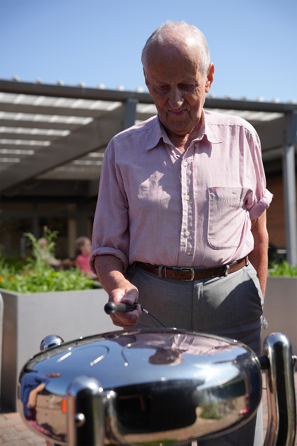 a senior male playing a stainless steel tongue drum in a senior living center