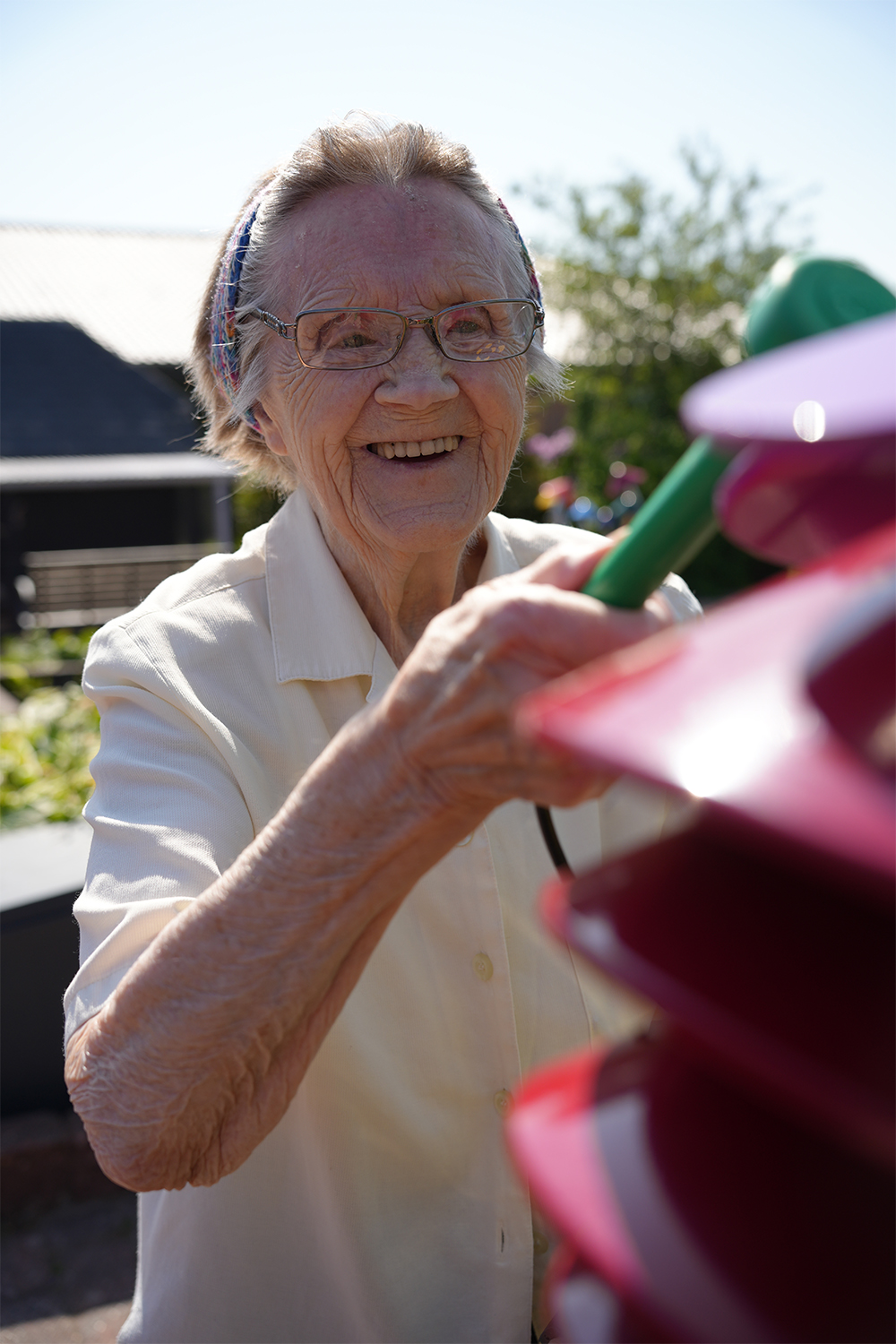 a senior lady playing an outdoor musical instrument shaped like a bell flower