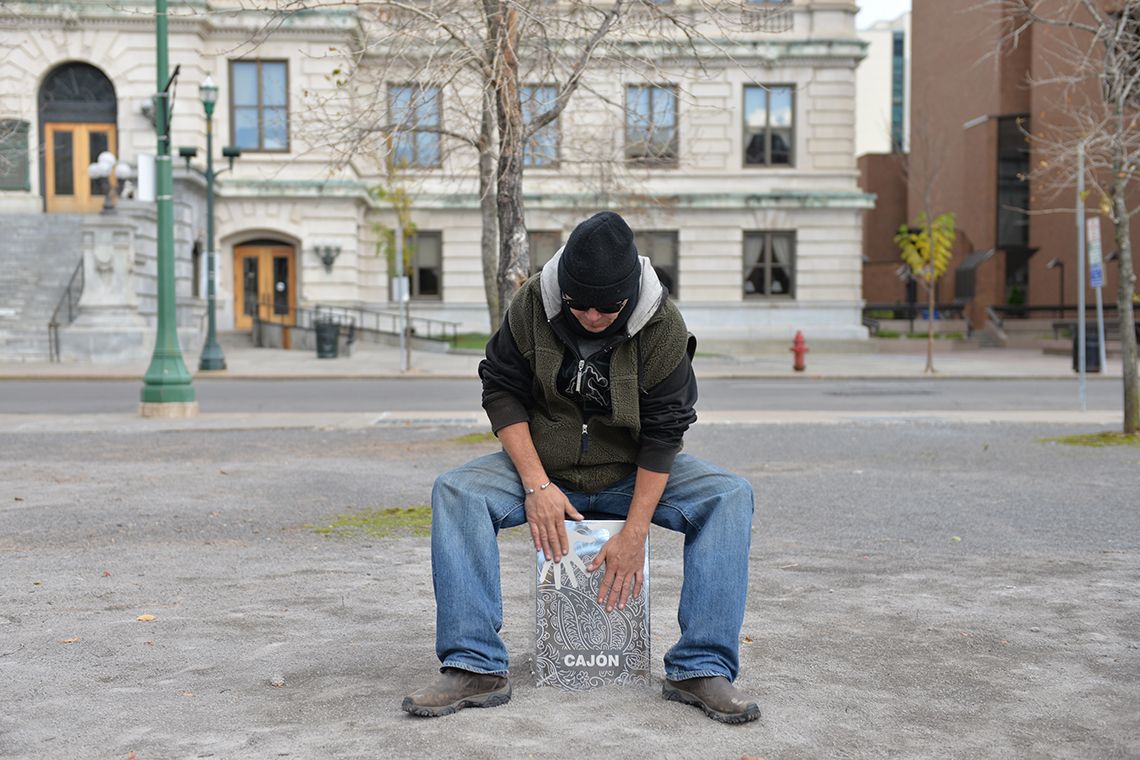 Man sat on stainless steel cajon drum in new york street