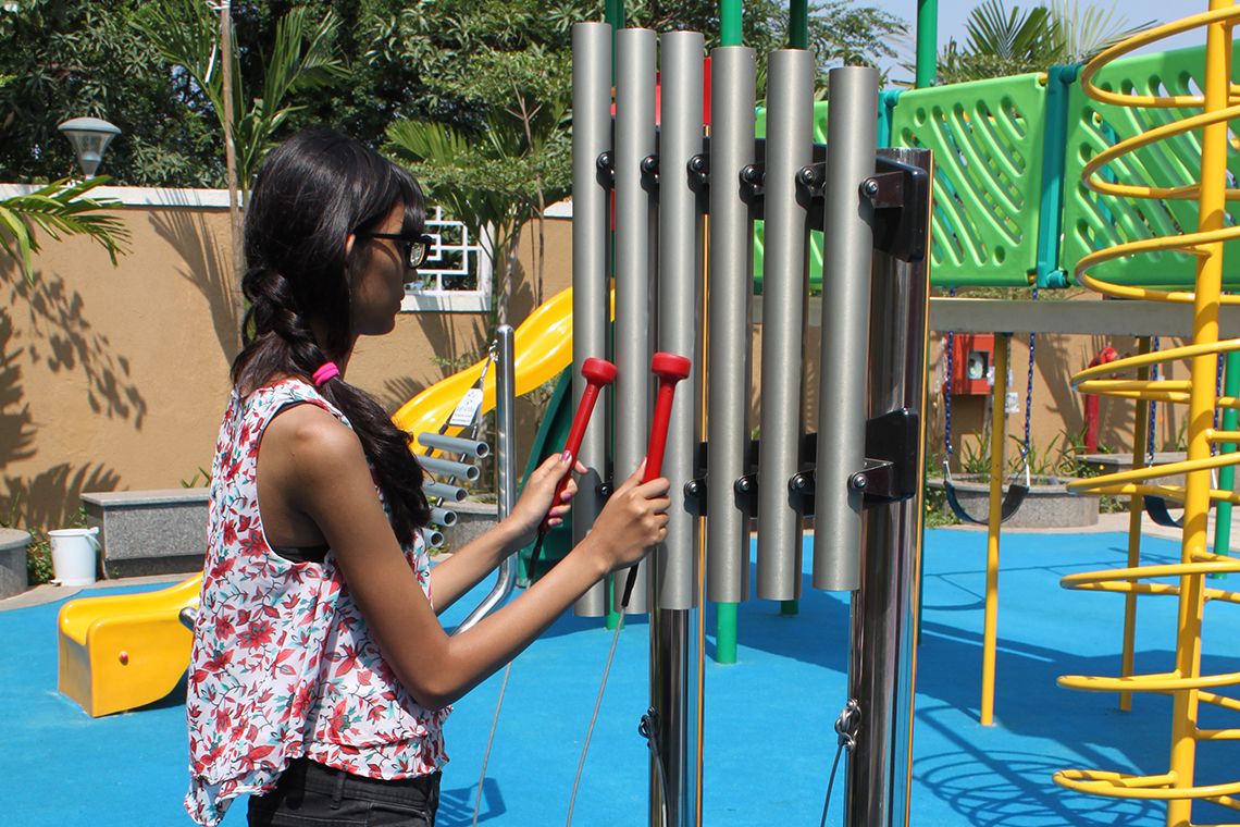 indian lady playing large outdoor musical chimes