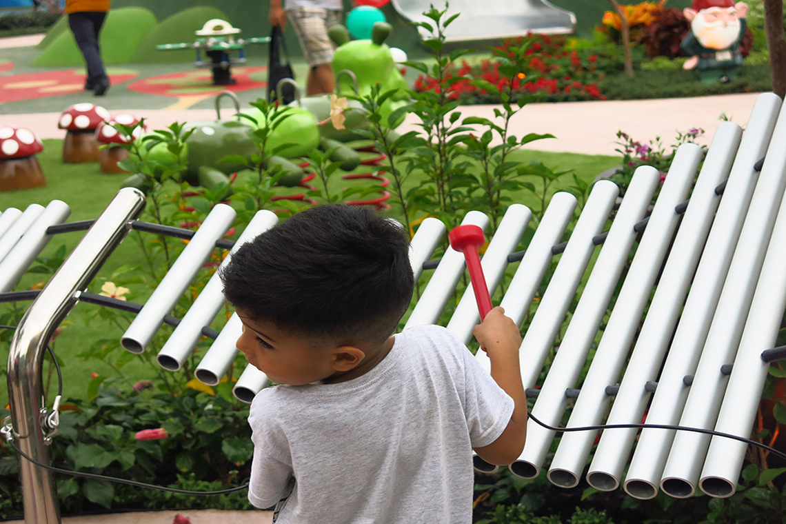 a young Brazilian boy playing a large outdoor musical instrument in a music park