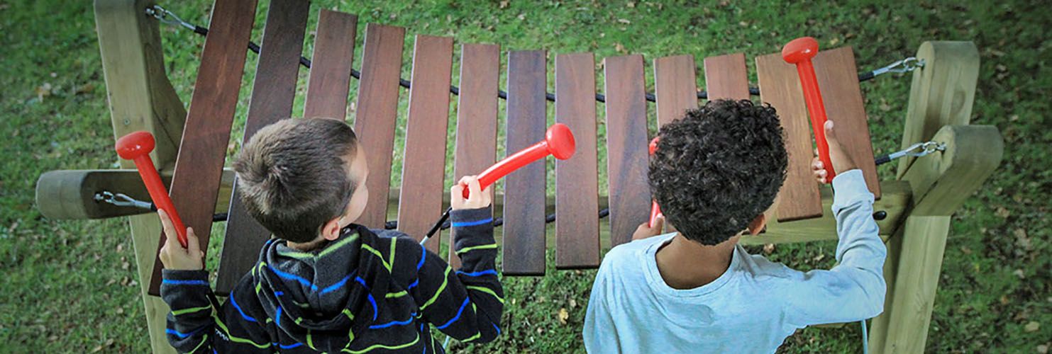 birds eye view of two boys playing a large outdoor marimba in a park