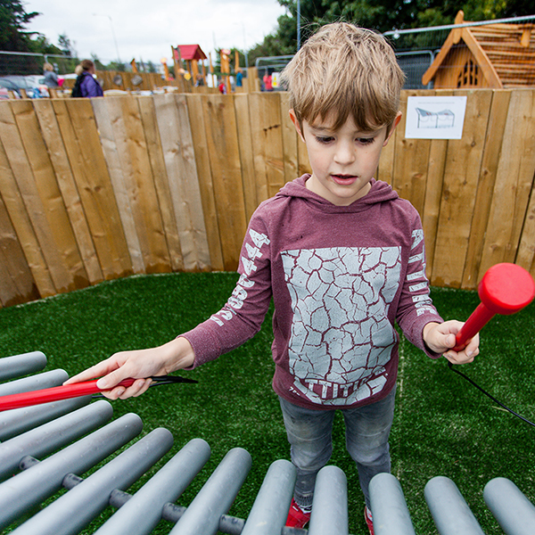 little boy playing a large outdoor musical instrument in the new playground at Greystones Co Wicklow Ireland