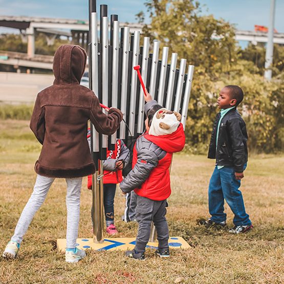 a small group of children playing on the outdoor musical instruments at the Leonel Castillo Community Center 