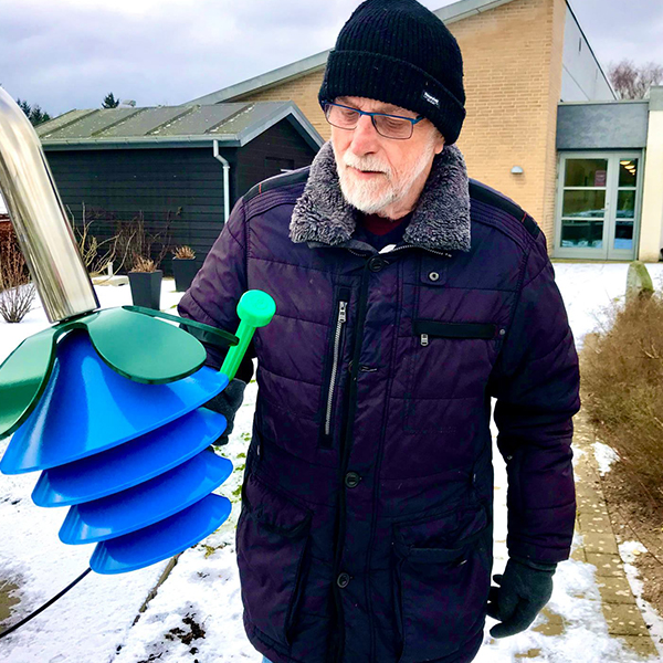 Senior Playing a Blue Harmony Bell outdoor musical flower bell in a Danish Care Home