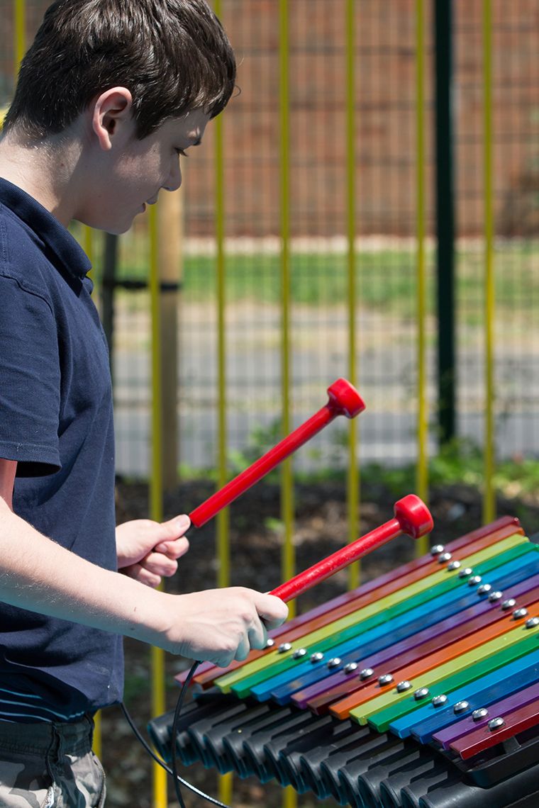 boys with special needs playing rainbow coloured chimes outdoors