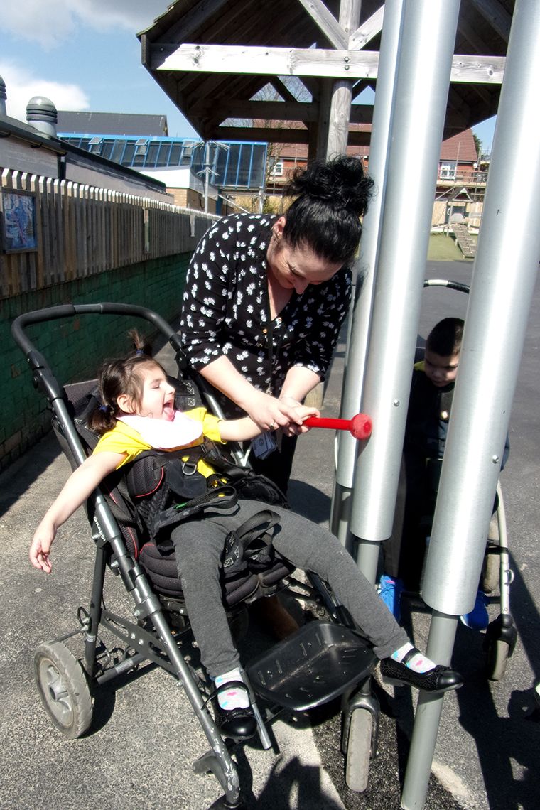 girl with special needs playing a large outdoor xylophone