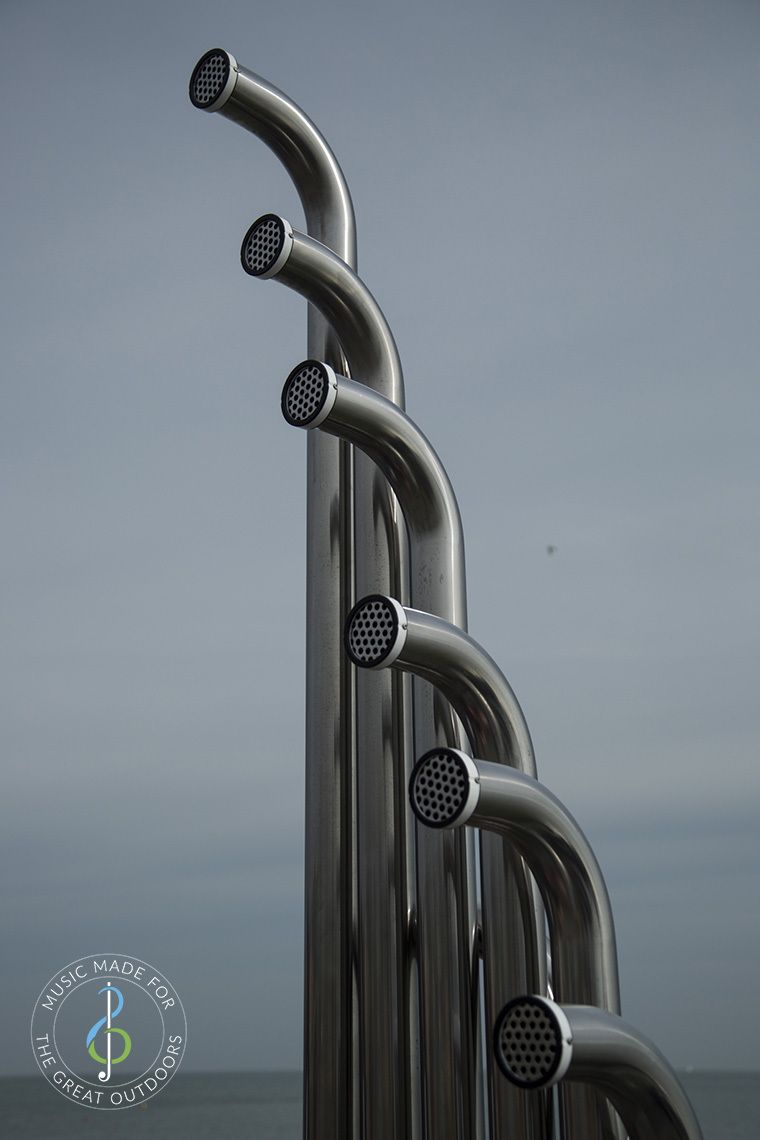 top ends of six large silver outdoor aerophones or slap tubes against blue sky