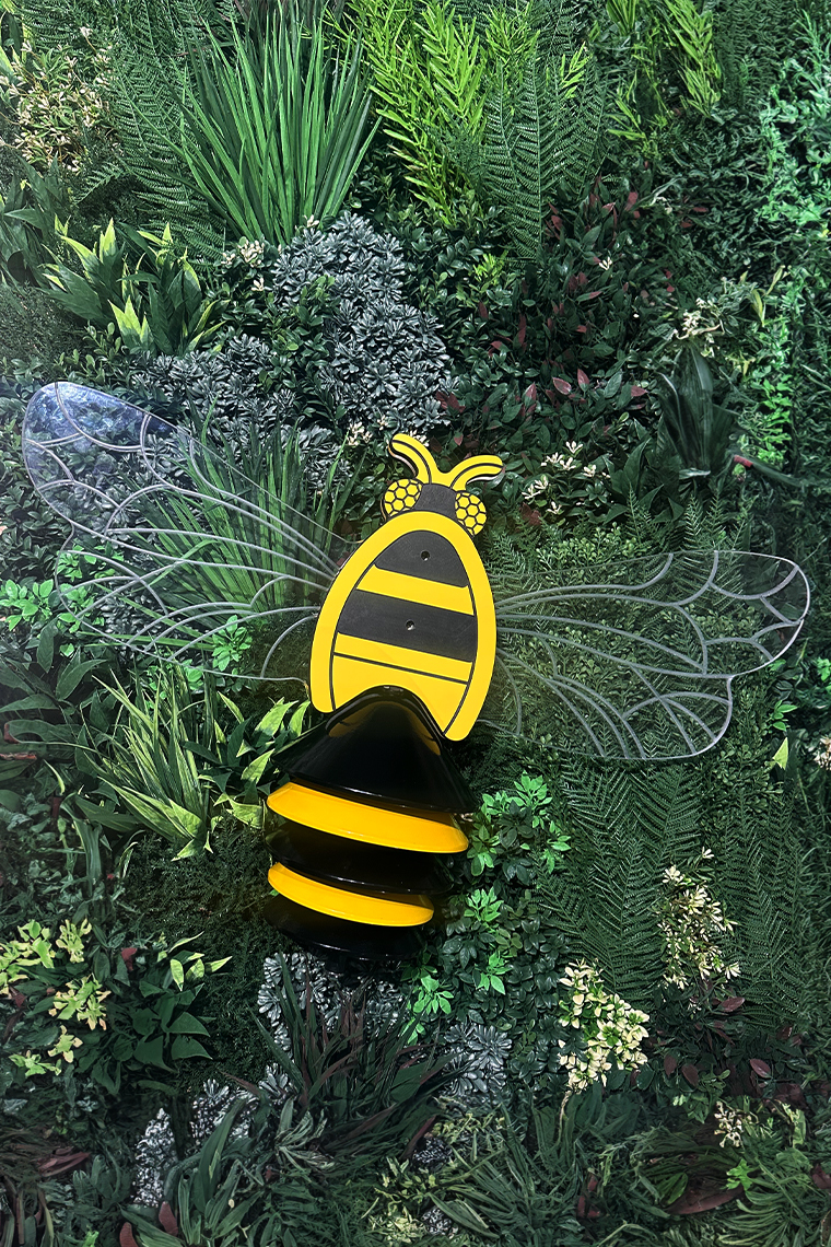 image of an outdoor musical instrument shaped like a bumblebee with black and yellow bells as a tail and acrylic wings