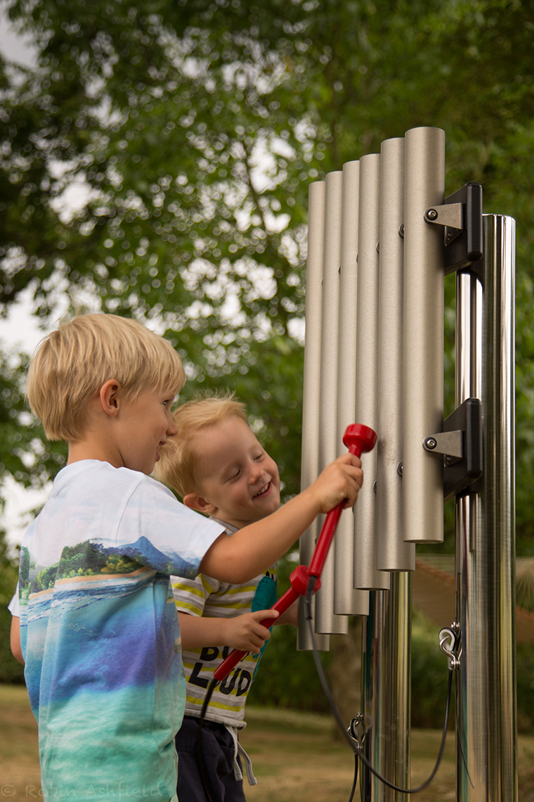 two little boys  playing on an outdoor musical instrument