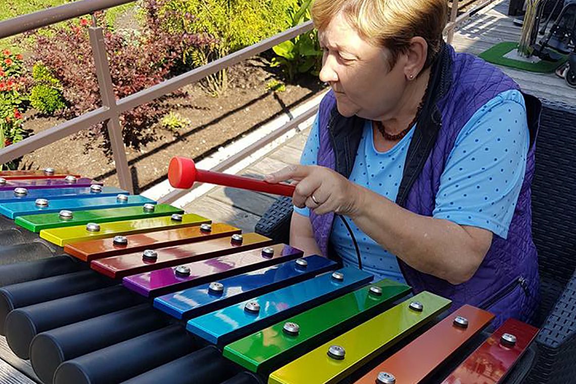 older lady in a wheelchair playing an outdoor musical instrument