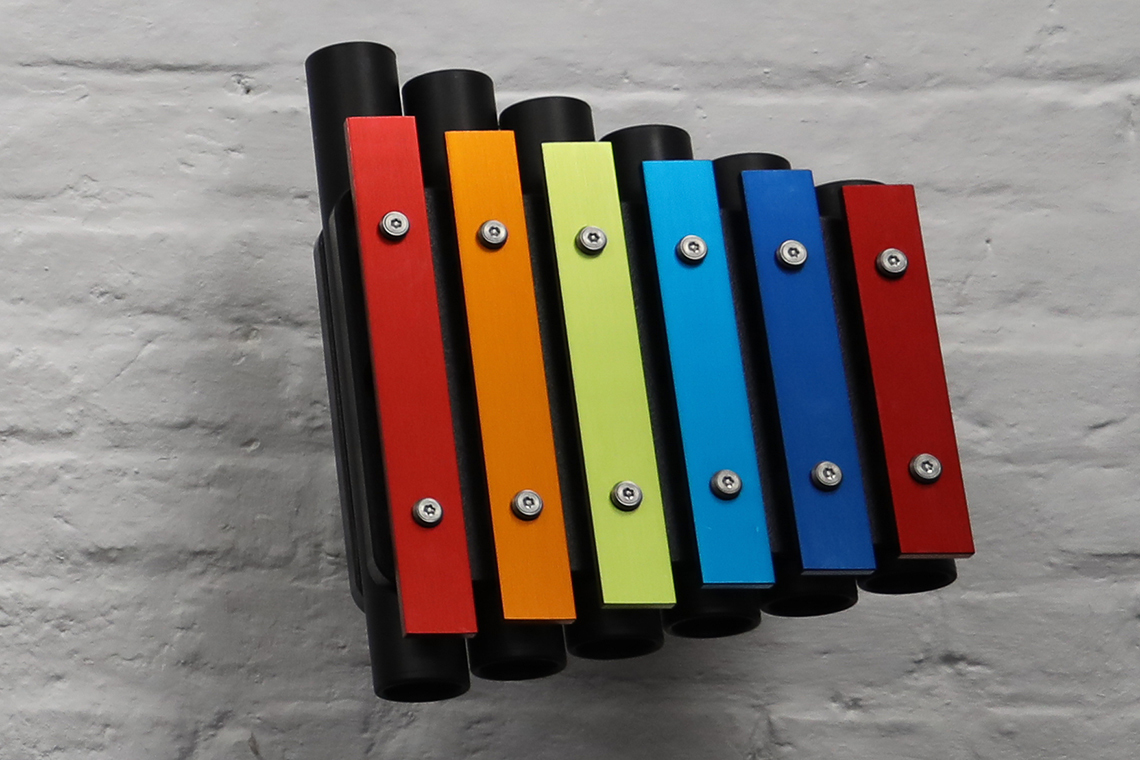 a small rainbow coloured outdoor metallophone for wall mounting suitable for nurseries and kindergartens